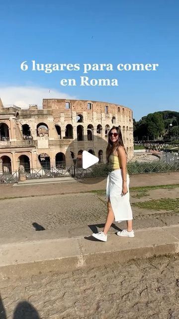 a woman walking down the street in front of an old building with roman ruins behind her