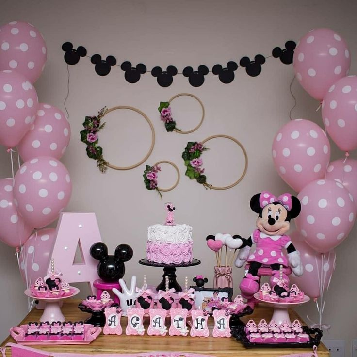 a minnie mouse themed birthday party with pink and black decorations, balloons, and cake