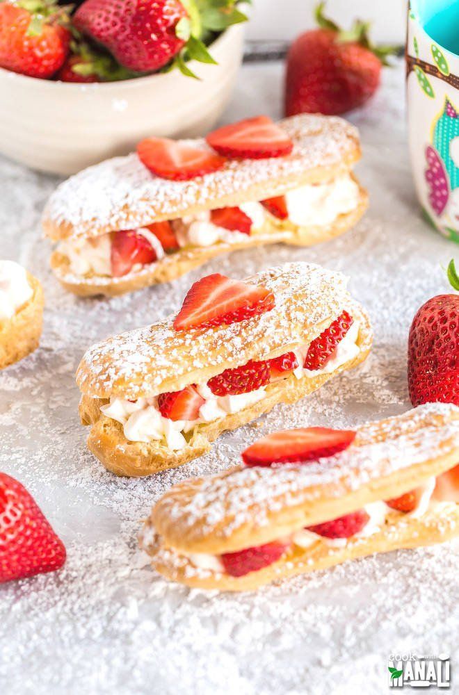 strawberry shortcakes with powdered sugar and fresh strawberries on the table next to them