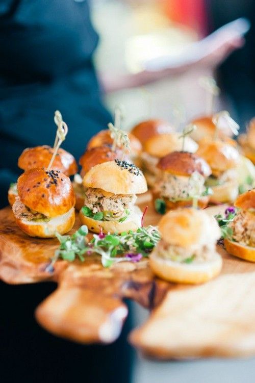 mini sandwiches are arranged on a wooden platter