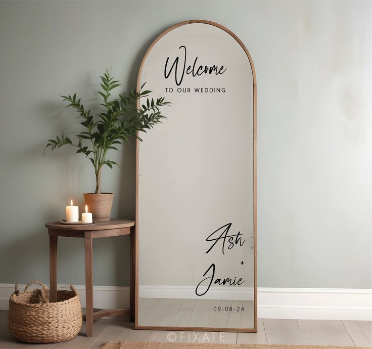 a welcome sign is displayed in front of a mirror with candles and a potted plant