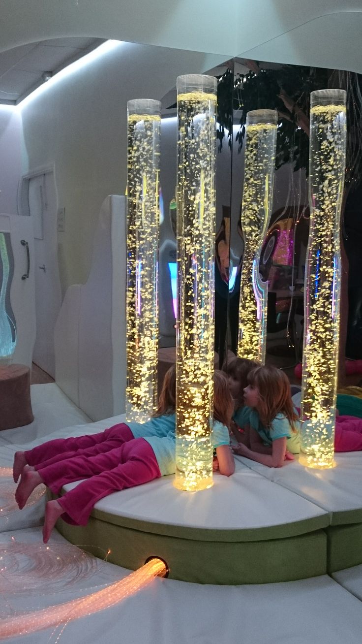 two children are laying on the floor in front of tall glass vases with lights