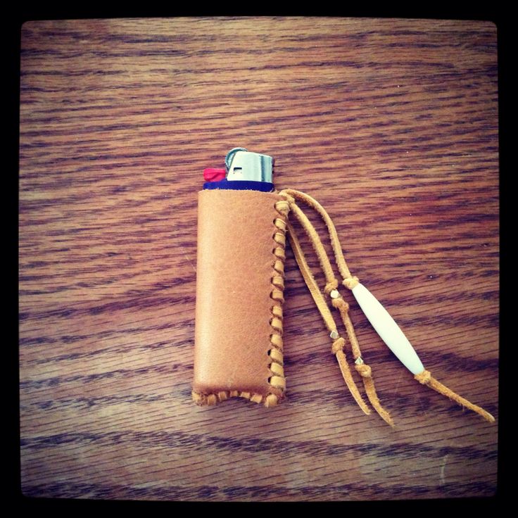 a leather case with a lighter in it sitting on a table next to a knife