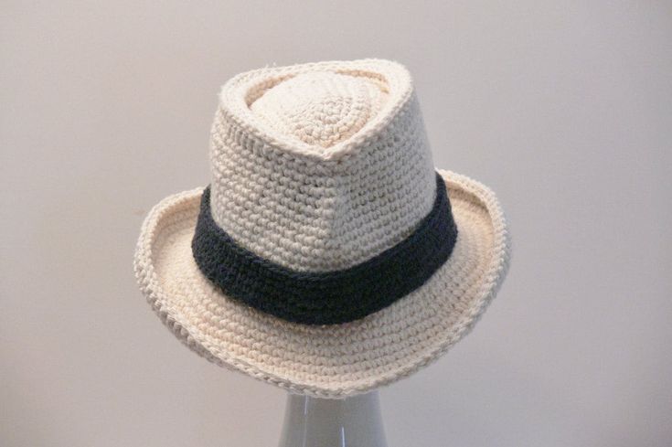 a white crocheted hat with a black ribbon around the brimmed band