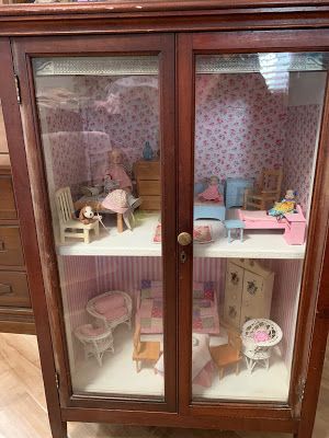 a doll house display case with furniture and dolls in the room on top of it