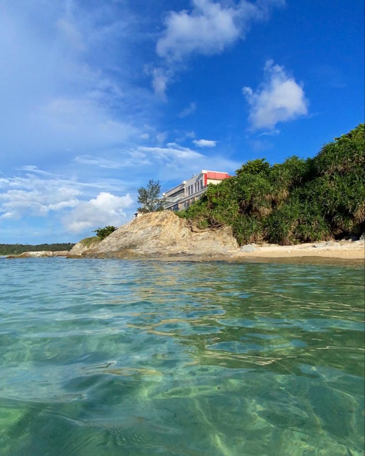 the water is crystal clear and there are some houses on top of the hill in the background