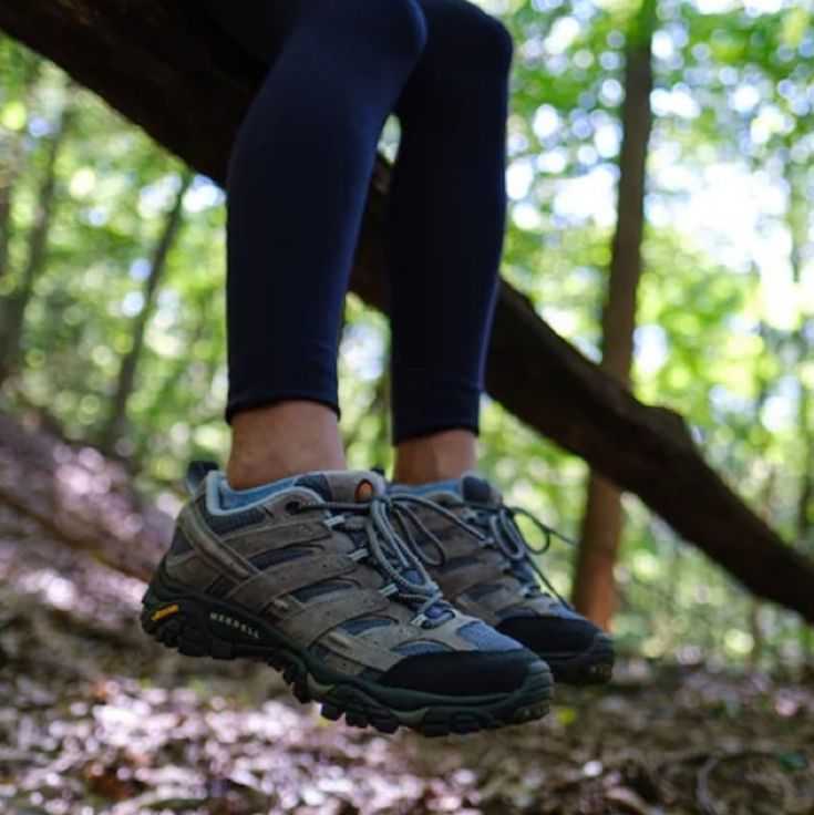 a person in blue leggings and grey shoes is hanging from a tree branch