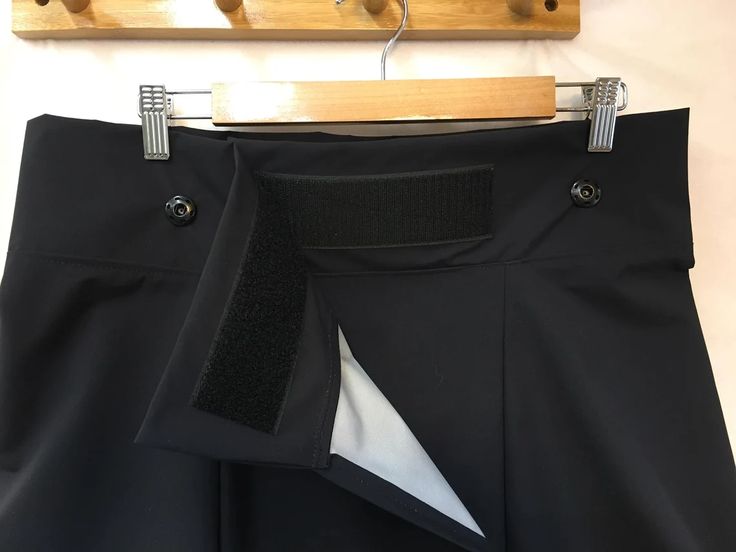 a pair of black pants hanging on a wooden hanger