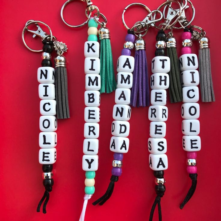 four key chains with letters and tassels attached to them on a red background