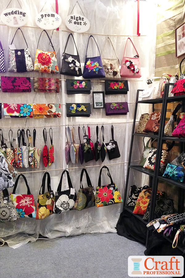 many purses are hanging on the wall in front of a display case with flowers