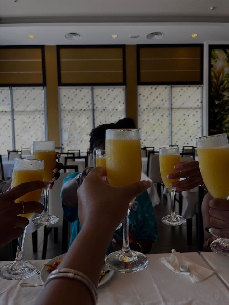 several people toasting with glasses of orange juice in front of them on a table