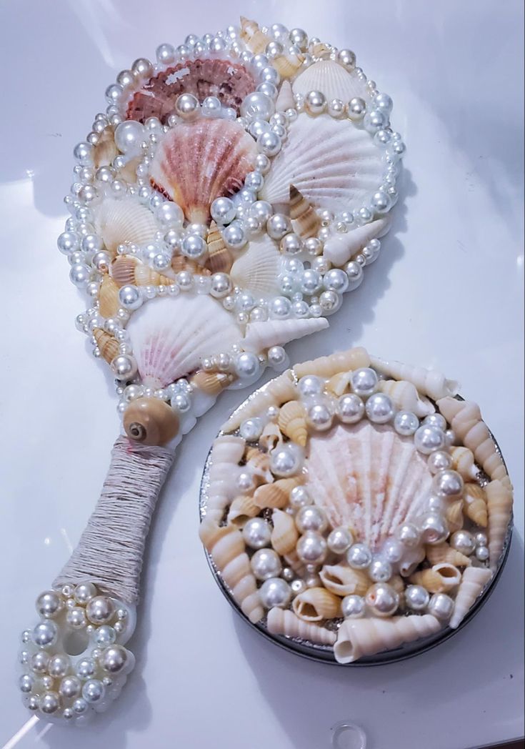 two seashells and pearls on a white surface