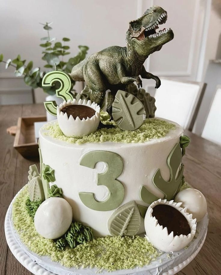 a dinosaur birthday cake is decorated with green and white decorations