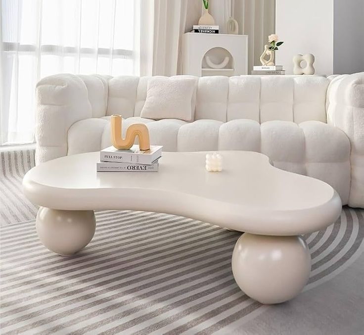 a living room with a large white couch and coffee table in front of a window