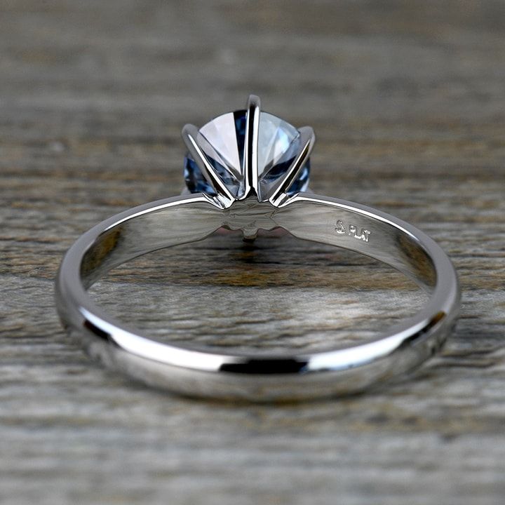 a close up view of a diamond ring on a wooden surface