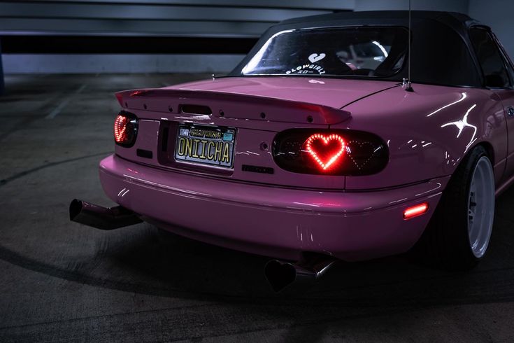 a purple car with a heart shaped tail light on it's side in a parking lot