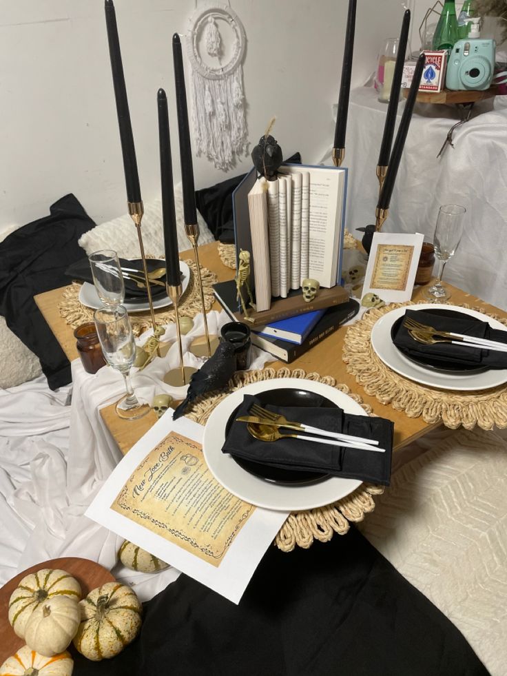 the table is set with black and gold place settings, books, candles, and other decorative items