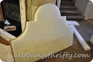 a white bed frame sitting in front of a fire place with stairs leading up to it