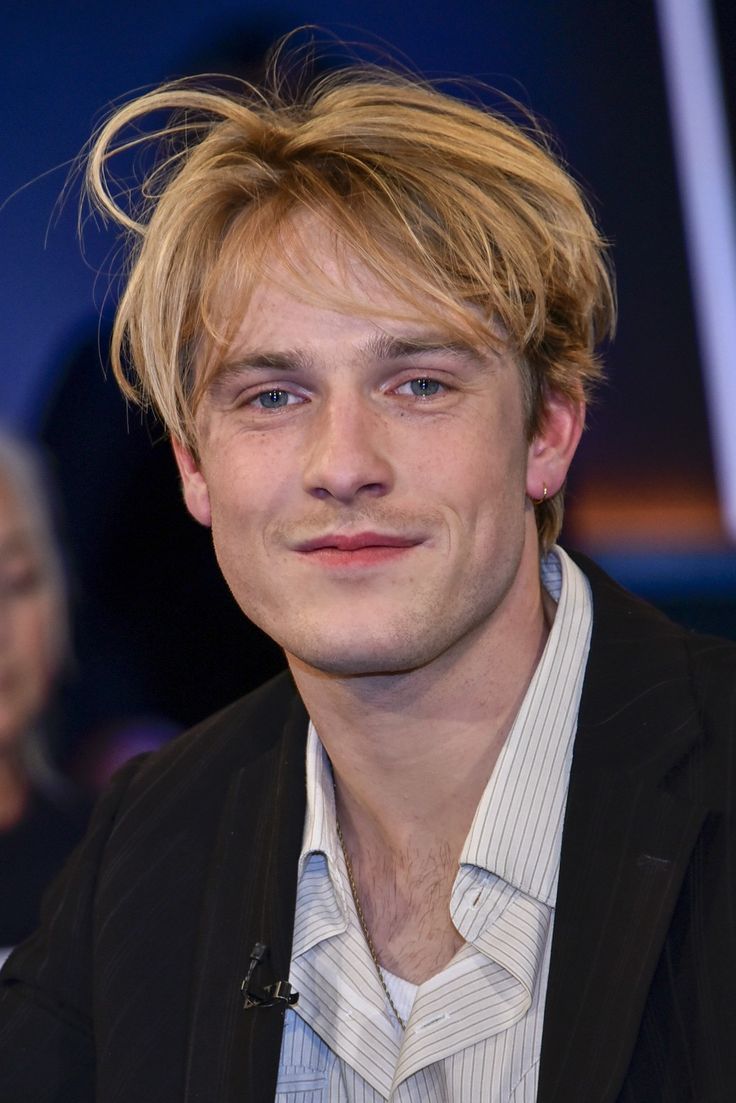 a young man with blonde hair sitting down