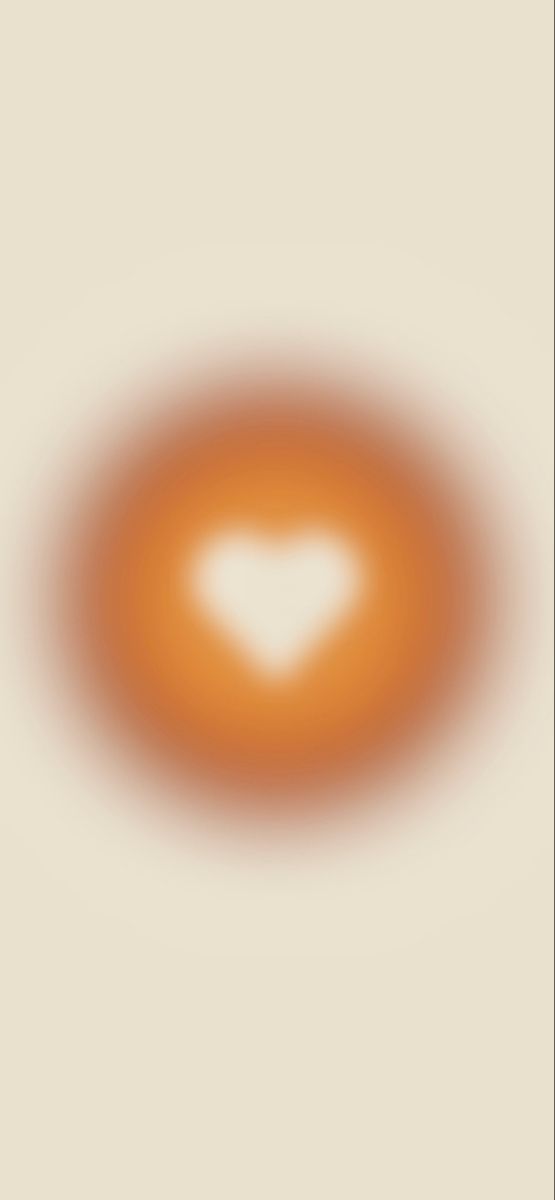 an orange circle with a white heart in the center on a beige background that appears to be blurry