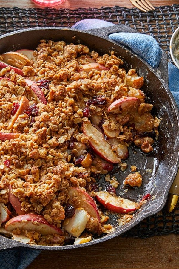 a skillet filled with apples and granola on top of a table