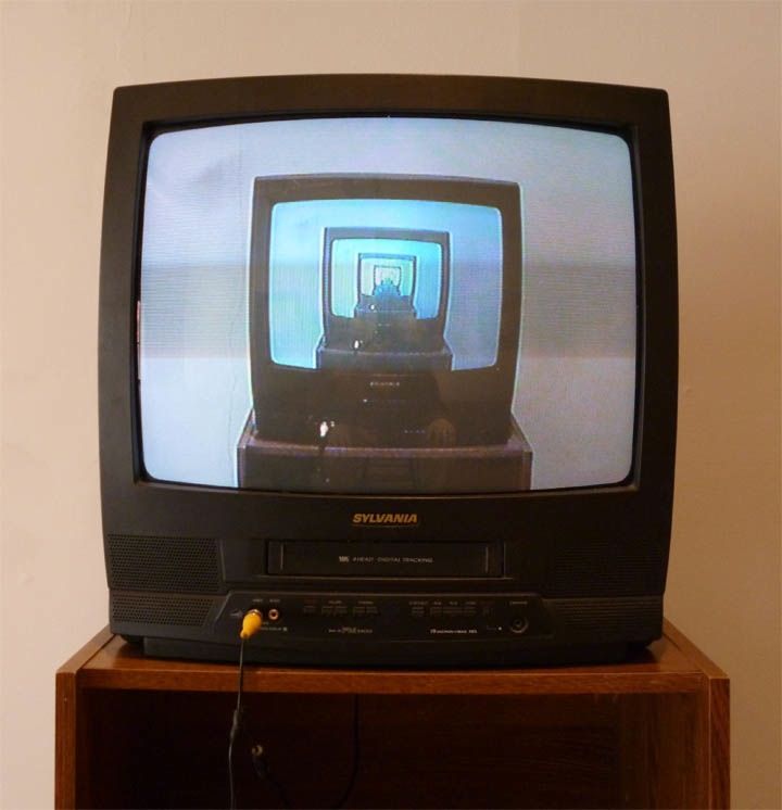 an old television sitting on top of a wooden stand with wires attached to it's sides