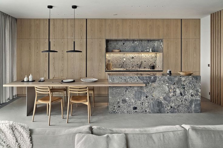 a modern kitchen and dining area with marble counter tops, wood cabinets, and white couches