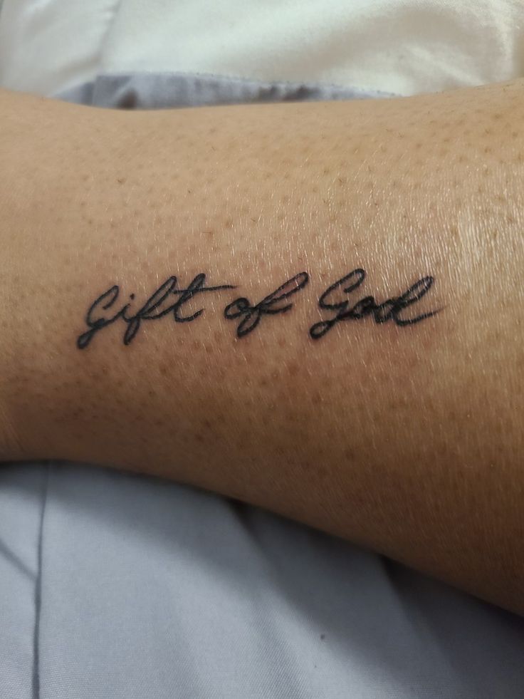 a person with a tattoo on their arm that says, gift of salt in cursive writing