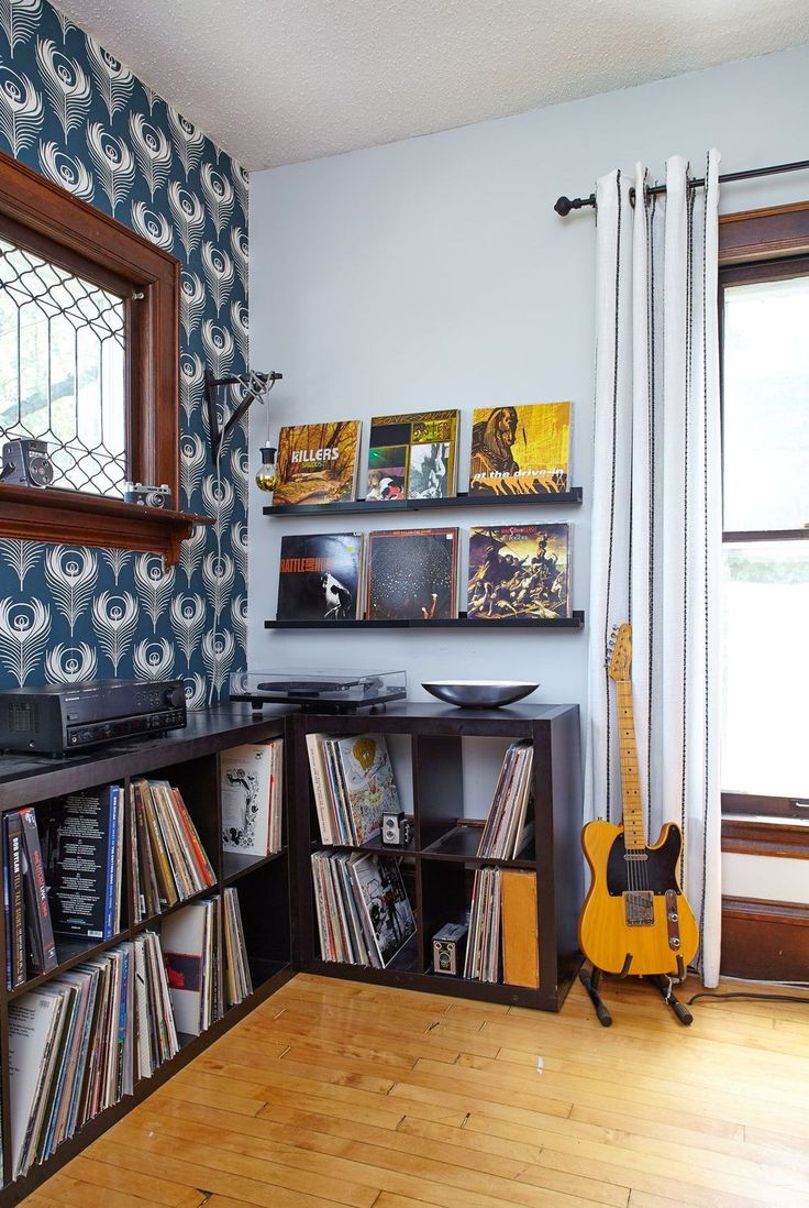 a room with a guitar, record player and various records on the shelves in it