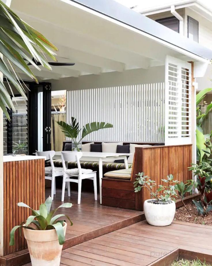 an outdoor living area with wooden decking and white chairs