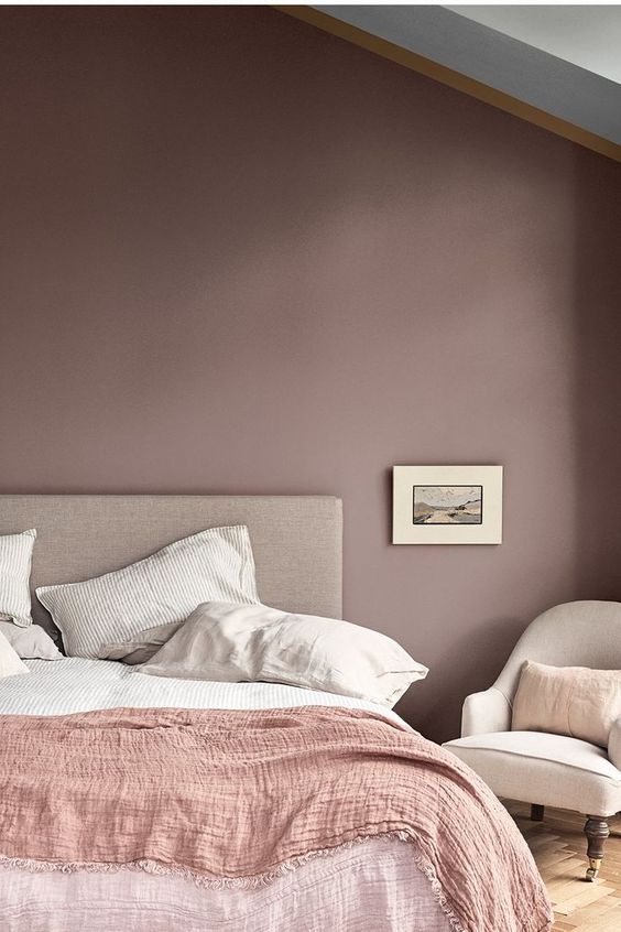 a large bed sitting next to a white chair in a bedroom on top of a hard wood floor