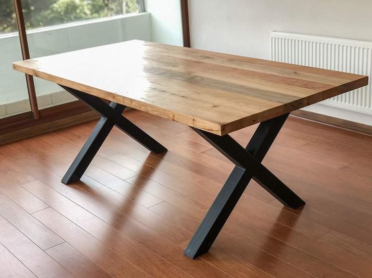 a wooden table sitting on top of a hard wood floor next to an open window