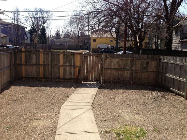 an empty backyard with wooden fence and dirt path leading to the back yard in winter