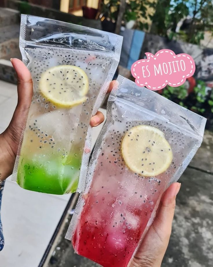 two bags filled with different colored drinks and one has a lemon slice on top of it