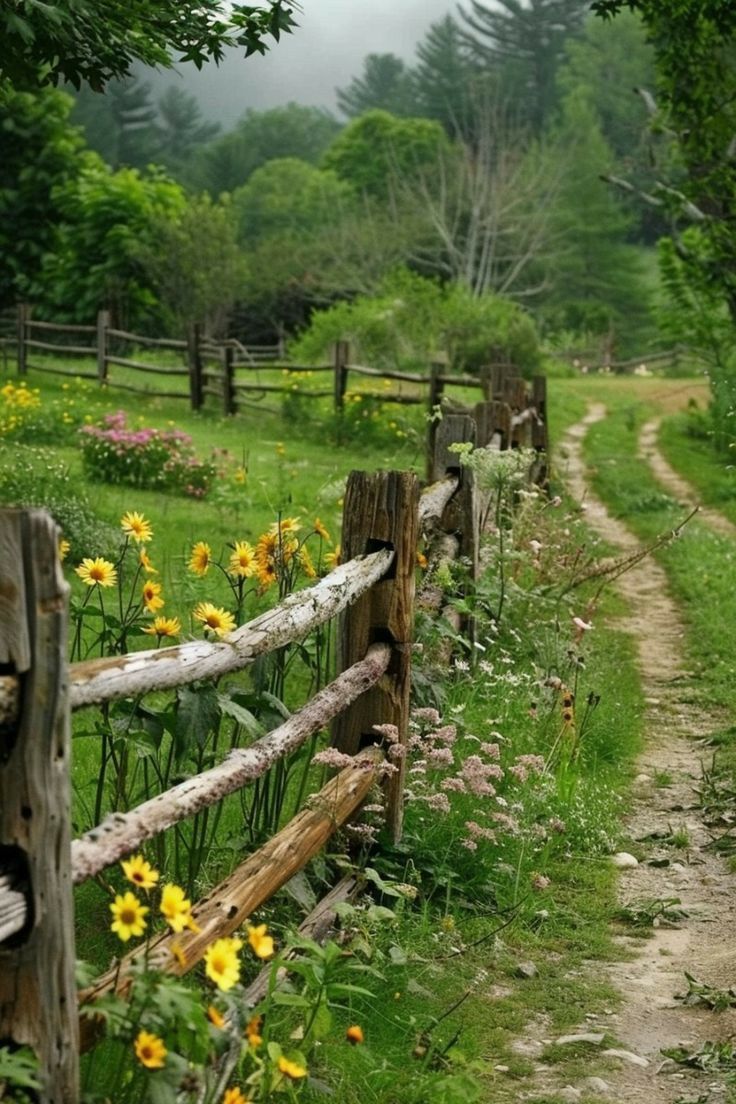 a wooden fence in the middle of a grassy field with flowers growing on both sides