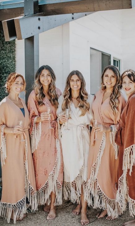 the bridesmaids are dressed in robes and posing together for a photo outside their home