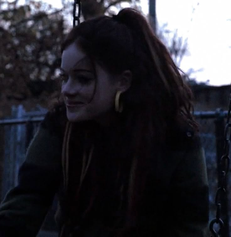 a woman with long hair sitting on a swing