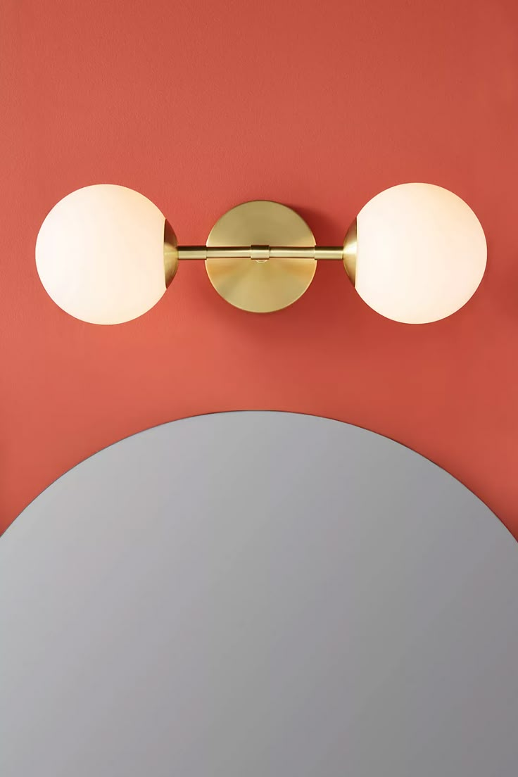 two lights on the wall above a mirror