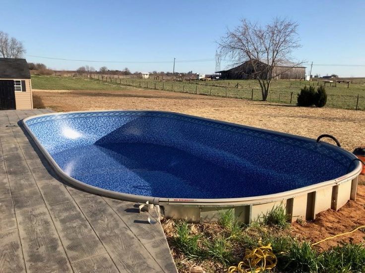 an above ground swimming pool in the middle of a yard with a wooden deck and fence around it