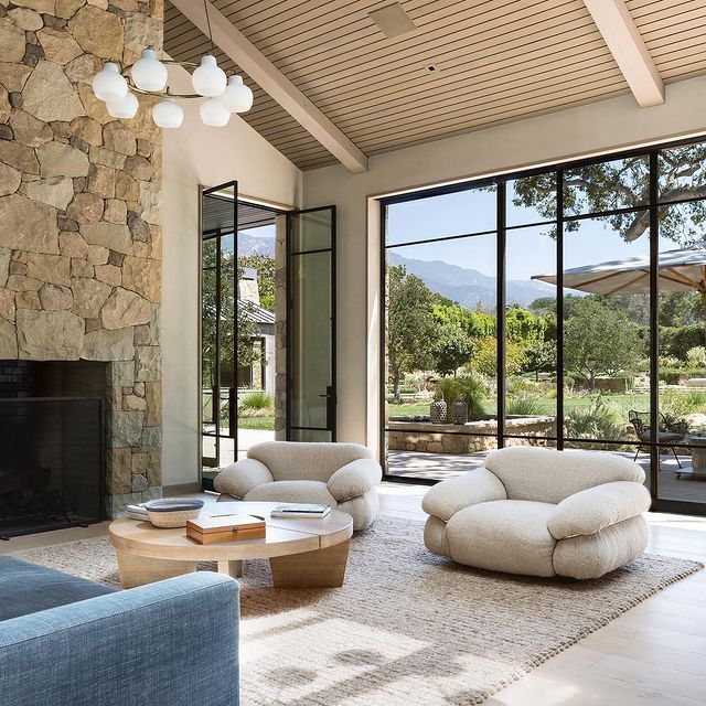 a living room filled with furniture and a fire place in front of a stone wall