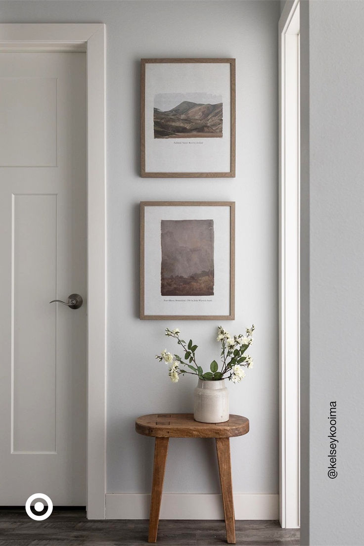 three framed pictures hang on the wall next to a small table with flowers in it