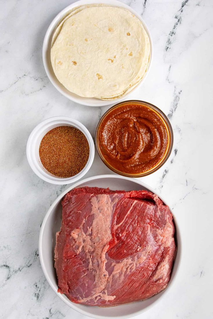 the ingredients to make an enchilada laid out in bowls on a marble surface