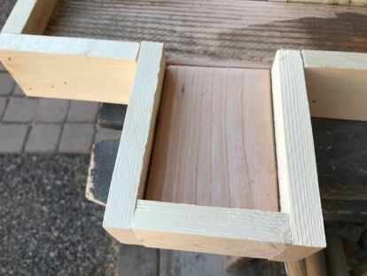 an unfinished piece of wood sitting on top of a wooden table next to a brick floor