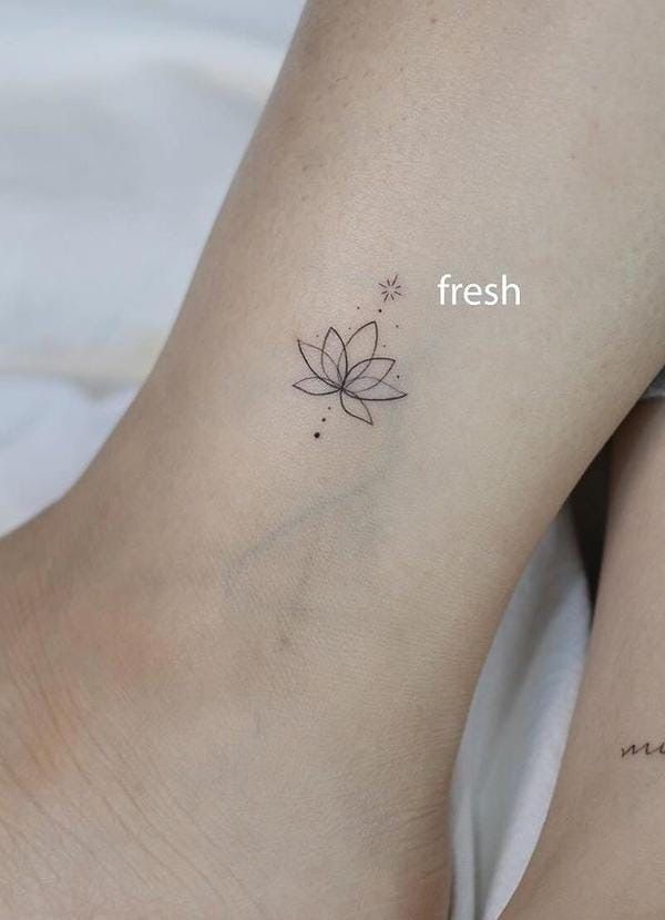 a woman's foot with a small flower tattoo on her left ankle and the word fresh written below it