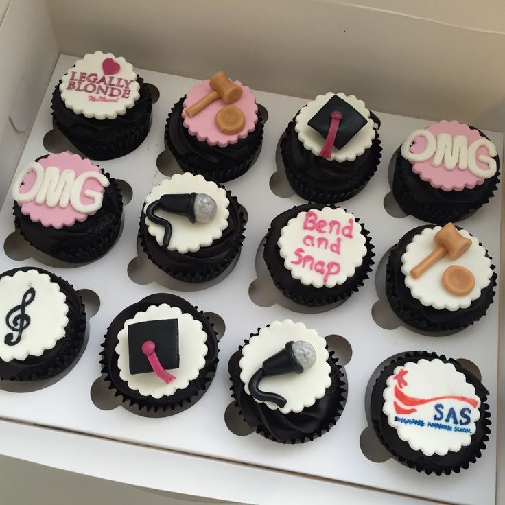 cupcakes decorated with black, white and pink icing are in a box