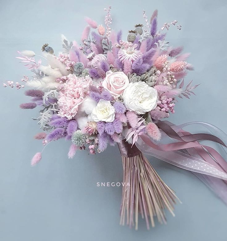 a bridal bouquet with pink and white flowers on a blue background is featured in this image