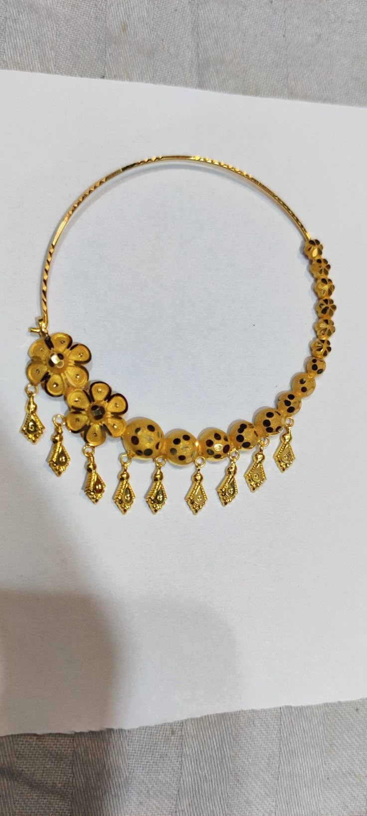 a gold necklace is displayed on a piece of paper