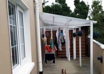 a dog sitting on the ground in front of a house with clothes hanging up to dry