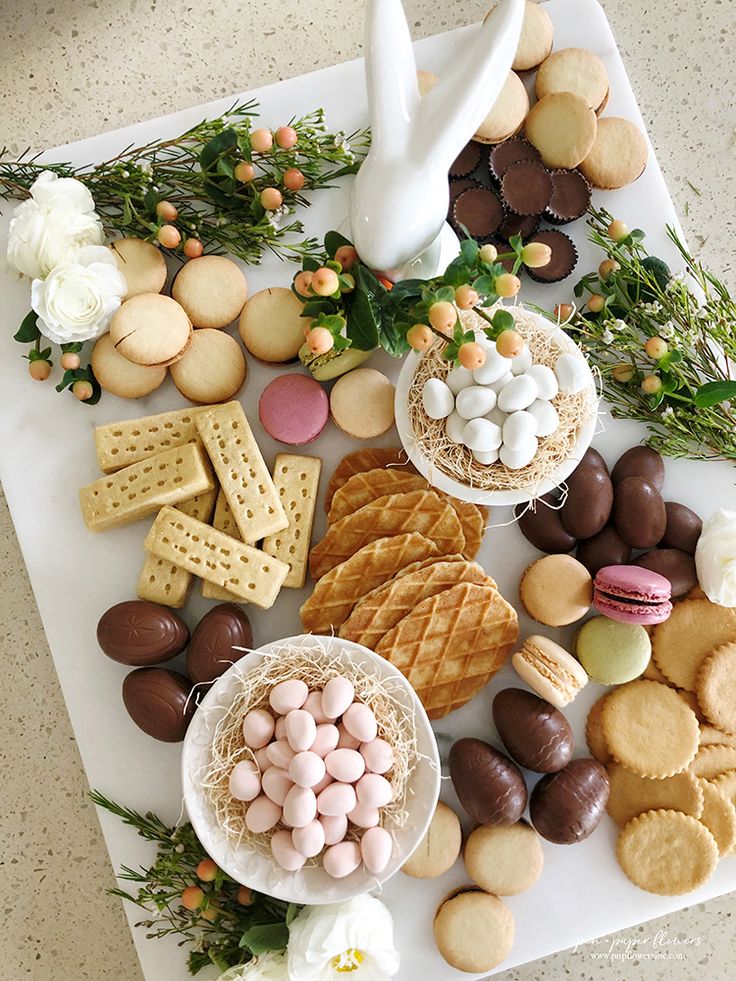 an assortment of cookies, crackers, and other treats on a white platter