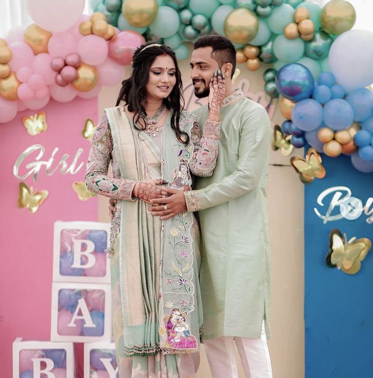 a man and woman standing next to each other in front of balloons